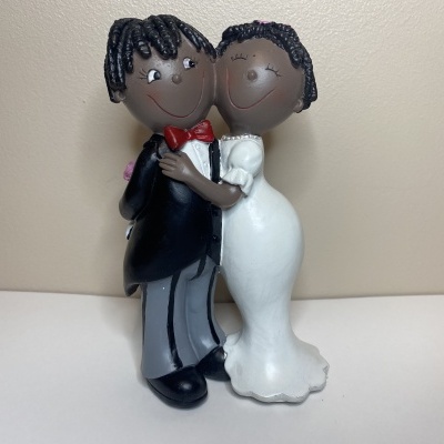 Figura decorativa de casal de noivos com roupa formal e cabelo preto.
