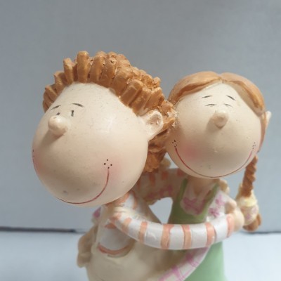 Figuras decorativas de uma menina e um rapaz sorridentes em cerâmica