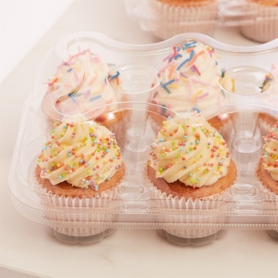 Caixa plástica com doze cupcakes decorados com creme branco e confetis coloridos