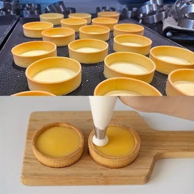 Tartes pequenas com base dourada e recheio amarelo, decoradas com creme branco em tábua de madeira