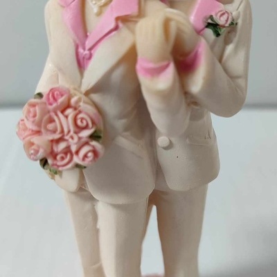 Figura decorativa de duas mulheres com fatos creme e rosa segurando bouquet de rosas