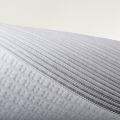 Colchão com duas texturas distintas, branca com quadrados e cinzenta com riscas verticais.