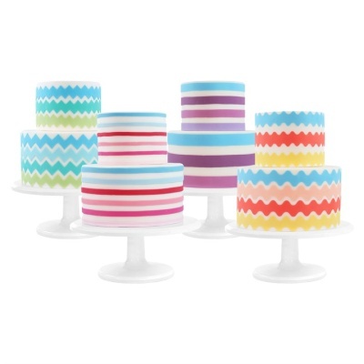 Cinco bolos decorados com padrões de riscas e zig-zag coloridos em suportes brancos