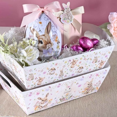 Cesta decorativa com padrão de coelhos, caixa em forma de ovo com laço rosa, flores artificiais e elementos decorativos