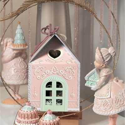 Casa decorativa rosa e verde com figuras femininas e bolos em tom pastel