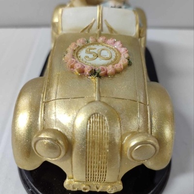 Figura decorativa de casal em carro dourado com detalhe 50 no capô