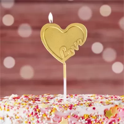 Vela dourada em forma de coração com a palavra 'Love' em bolo decorado