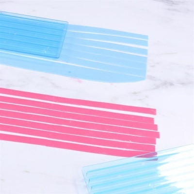 Acessórios plásticos azul translúcido e rosa com ranhuras sobre fundo branco mármore