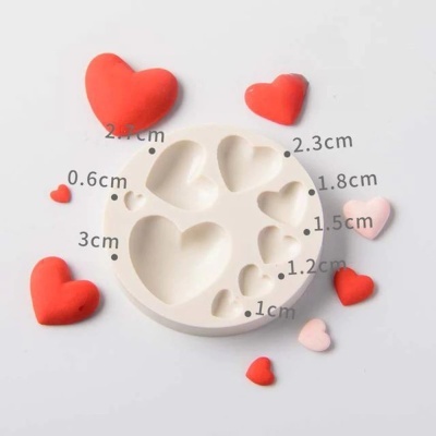 Molde silicone branco com cavidades em forma de coração e corações coloridos