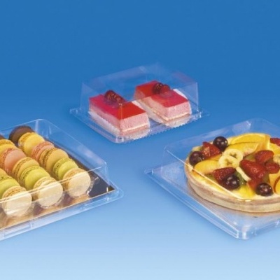 Três embalagens plásticas transparentes com bolachas, bolos e tarte de frutas sobre fundo azul