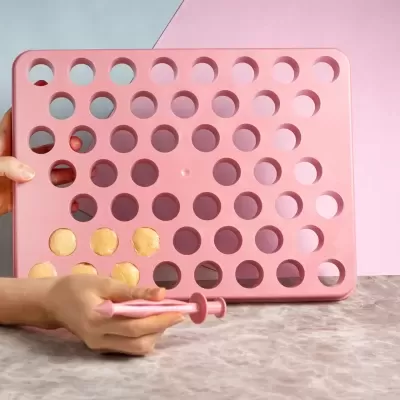 Tabuleiro quadrado rosa com buracos redondos e mãos segurando