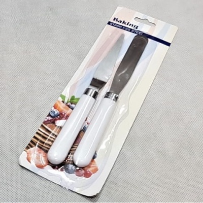 Conjunto de duas espátulas de cozinha com cabo branco e lâmina metálica em embalagem de plástico sobre cartão.