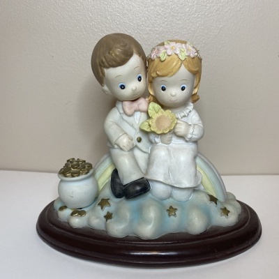 Figura decorativa de casal em roupas de casamento sobre arco-íris e nuvens.»