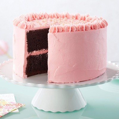 Bolo de chocolate com cobertura e decoração cor-de-rosa num suporte branco