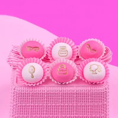 Doce redondo decorado com símbolo dourado em cima de tecido rosa.