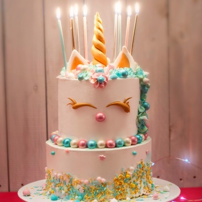Bolo de unicórnio branco com decoração colorida e velas acesas