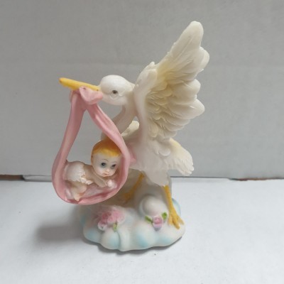 Figurina de cegonha branca com bebé embrulhado em pano cor-de-rosa