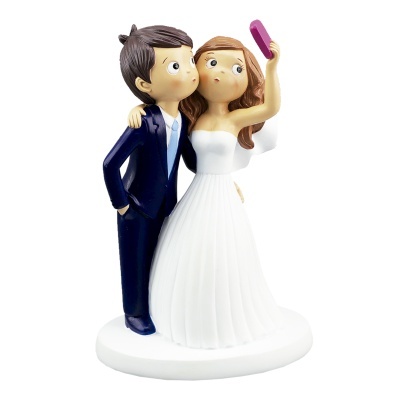 Estatueta de casal de noivos a tirar uma selfie, noivo de fato azul e noiva de vestido branco.