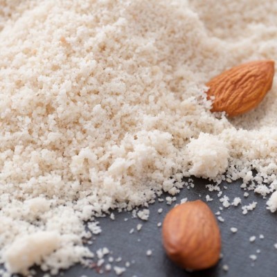 Farinha fina clara com duas amêndoas marrons sobre superfície escura