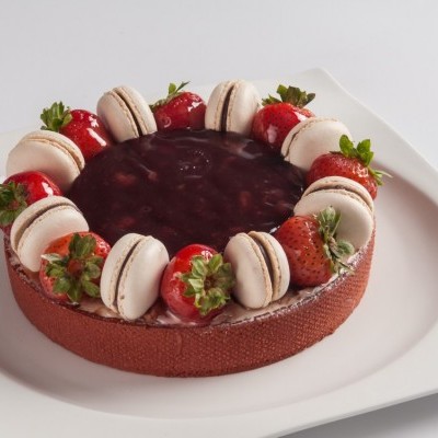 Tarte de chocolate decorada com morangos e macarons num prato branco