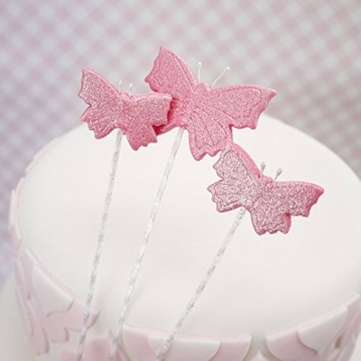 Velas em forma de borboleta cor-de-rosa sobre bolo branco