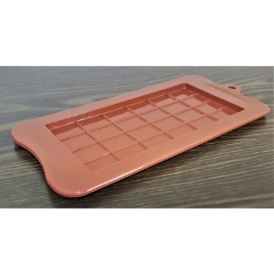 Tabuleiro retangular cor de terracota com secções quadradas e bordas arredondadas sobre mesa de madeira