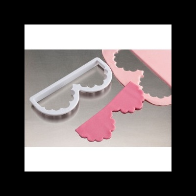 Ferramenta de corte em plástico branco e massa rosa sobre superfície metálica