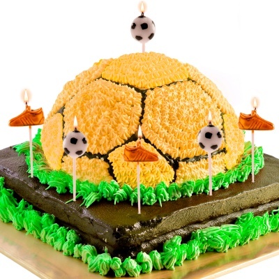 Bolo decorado de futebol amarelo e preto com velas em forma de bola e chuteira