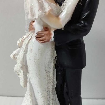 Figuras decorativas de noivos em resina, vestido branco com véu e fato preto.