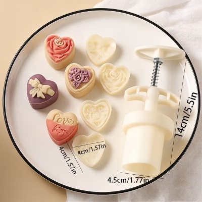 Conjunto de cortadores e carimbos de coração para biscoitos em prato branco.