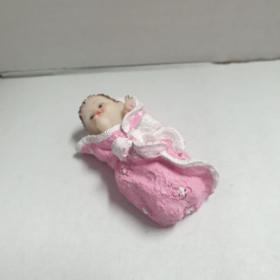 Boneco de bebé em resina vestido de rosa e branco numa superfície branca