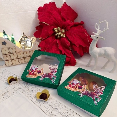 Caixas verdes com bombons, flor vermelha e rena branca decorativa