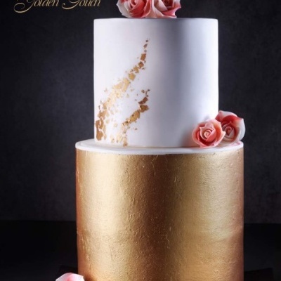 Bolo de dois andares branco com decoração dourada e rosas cor-de-rosa