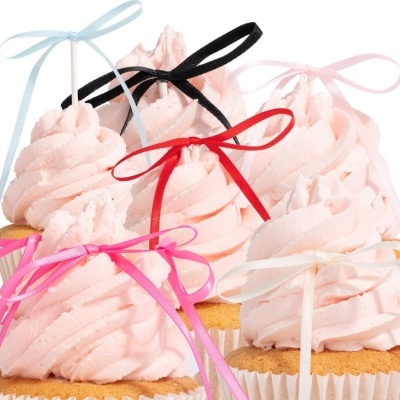 Cupcakes com cobertura rosa e fitas coloridas amarradas em laços
