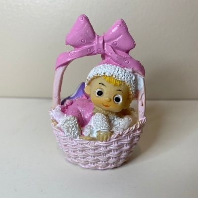 Figura decorativa de bebé num cesto rosa com arco