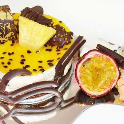 Bolo decorado com frutas e chocolate sobre placa espelhada