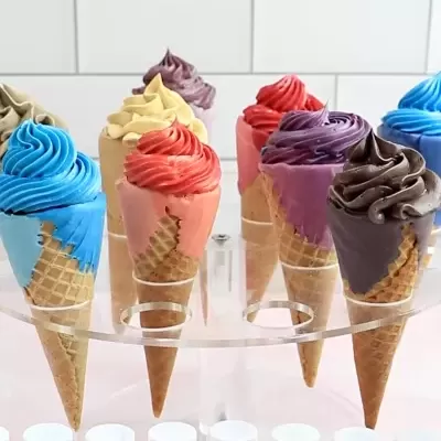 Oito cones de gelado coloridos em suporte transparente frente a fundo de azulejos brancos