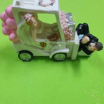 Figura decorativa de carro de noivos em cerâmica em fundo verde