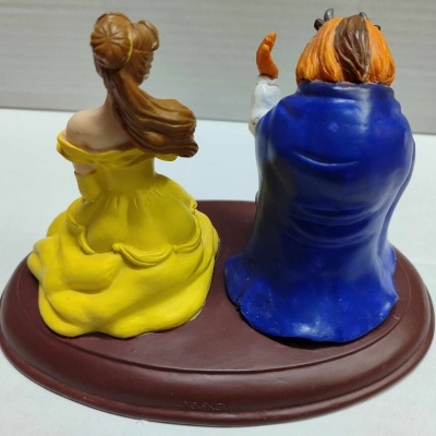 Estatuetas de duas personagens sentadas, uma com vestido amarelo e outra com casaco azul, base castanha.