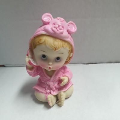 Boneco de bebé em roupão rosa com capuz de urso sentado