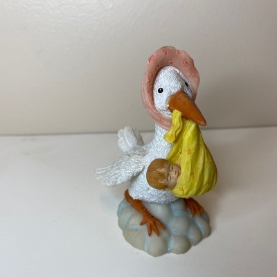 Figura decorativa de cegonha cerâmica com bebé na bandana amarela