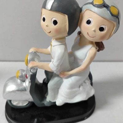 Figura decorativa de casal em scooter prateada com capacetes cinza