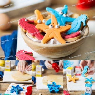 Bolachas decoradas em forma de estrelas-do-mar e cavalos-marinhos coloridas numa tigela de madeira com imagens do processo de preparação na cozinha.