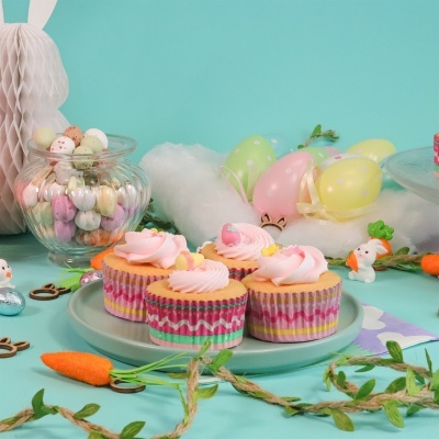 Cupcakes com glacê rosa e decoração de Páscoa com ovos, coelhos e cenouras artificiais