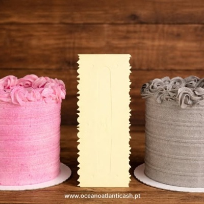 Dois bolos decorados, um rosa e outro castanho claro, sobre superfície de madeira.