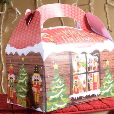 Caixa de presente de Natal em papel cartão com decoração de árvores, bonecos soldado e texto 'Merry Christmas'.