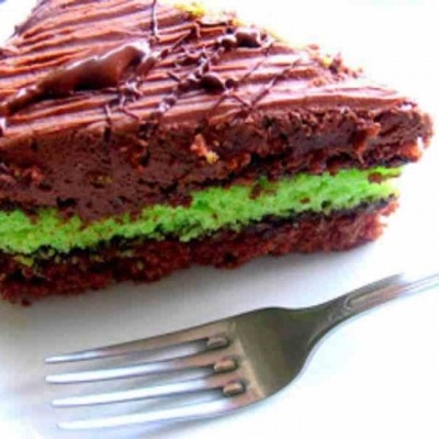fatia de bolo de chocolate com recheio verde num prato branco com um garfo