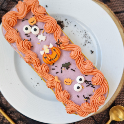 Bolo decorado com creme roxo e rosa alaranjado com decoração temática de Halloween