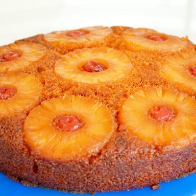 Bolo redondo com ananás e cerejas num prato azul