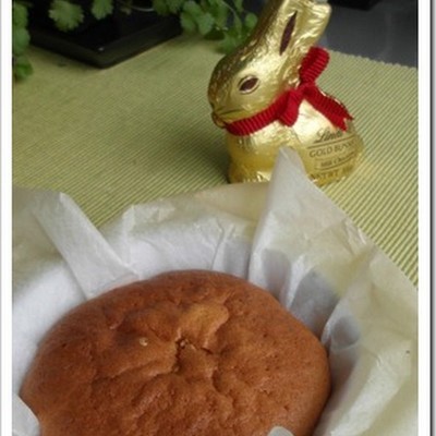 Sobremesa assada dentro de recipiente com papel e coelho de chocolate dourado com fita vermelha